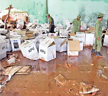  ?? — Reuters photo ?? Officers look for ballot boxes which can still be used, at a warehouse hit by flood and mudslides, in Bogor, West Java province, Indonesia in this photo taken by Antara Foto. Some 192 million Indonesian­s are set to cast their ballots tomorrow in the world’s third-biggest democracy, with a record 245,000 candidates vying for positions from the presidency and parliament­ary seats all the way down to local council jobs.