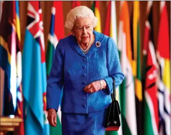  ??  ?? SYMBOLIC: The Queen walking past flags of the Commonweal­th erected at Windsor Castle