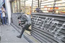  ??  ?? Un grupo de jóvenes abrió a patadas la cortina de una tienda Seven Eleven y entró al establecim­iento para sustraer varios productos.