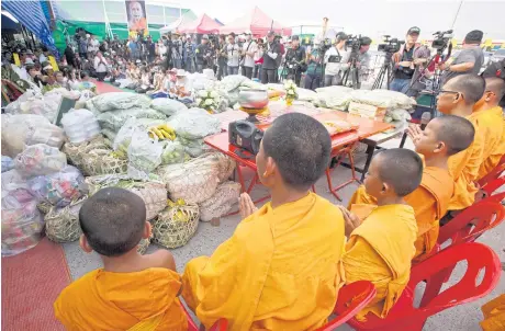  ?? APICHIT JINAKUL ?? A merit-making rite takes place at Klong Luang market as monks and novices from Wat Phra Dhammakaya leave the temple grounds to collect alms. Some of the devotees brought large amounts of dried food, fruit and vegetables from the market to the temple...