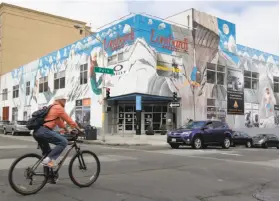  ?? Paul Chinn / The Chronicle 2014 ?? A bicyclist rides in 2014 past the old Lombardi Sports building at Polk and Jackson streets in S. F., where Whole Foods is planning to put a 365 store.