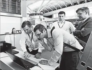  ?? SERGEI CHUZAVKOV/AP ?? Employees use a laptop computer to work at Boryspil airport in Kiev, Ukraine, last month. A new outbreak of malicious data-scrambling software is causing mass disruption­s.