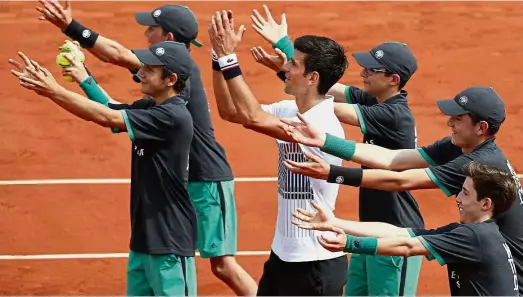  ?? — AP ?? The more the
merrier: Novak Djokovic (in white T-shirt) celebratin­g with the ball boys after winning his first-round match against Marcel Granollers at the French Open yesterday.