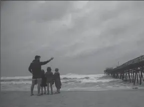  ?? TRAVIS LONG/THE NEWS & OBSERVER ?? Joel Sullivan, 30, of Morehead City, N. Carolina, left, stands on the beach with his children from left, Nona, 7, Cecile, 5, and Henry, 7, near the Oceanana Pier &amp; Pier House Restaurant in Atlantic Beach on Thursday as Hurricane Florence approaches the Carolinas.