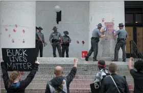  ?? THE ASSOCIATED PRESS ?? Ohio State Highway Patrol troopers try to clean paint off of the Ohio Statehouse after a small group of protestors painted red hands, to “signify the blood on police hands” they said, during a demonstrat­ion in Columbus, on June 18.