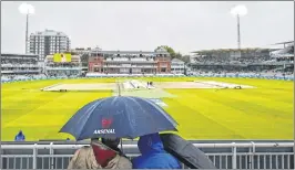  ??  ?? Spectators shelter under umbrellas as rain delays play during the second day of the third Test between England and West Indies at Lords cricket ground on Friday. England was bowled out on 194 in their first innings on a rain-marred day