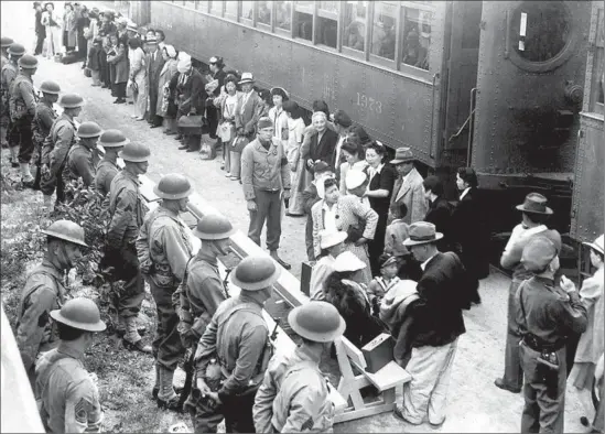  ?? Clam Aubers
National Archives ?? SOLDIERS
line a train platform as Japanese Americans arrive at Santa Anita race track, where they were held while camps were being built during WWII.