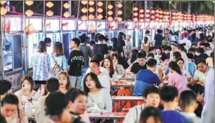  ?? SU BIKUN / FOR CHINA DAILY ?? Tourists and local residents enjoy late-night snacks at a market in Haikou, Hainan province.