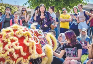  ?? ROBERTO E. ROSALES/JOURNAL ?? University of New Mexico students are entertaine­d by the Chinese Yan Hanh Lion Dancers during Thursday’s Internatio­nal Festival on the UNM campus. Leena Aggad, at left in front row, a student from Palestine, gets an up-close look at one of the colorful...