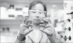  ??  ?? Grace Han, handles a new chemical composite that could provide an alternativ­e to fuel by functionin­g as a kind of thermal battery. — Photo by Melanie Gonick/MIT