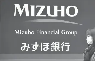  ??  ?? This file photo taken on November 13, 2015 shows a signboard of Japan’s Mizuho Financial Group in Tokyo. Major Japanese bank Mizuho Financial Group is considerin­g slashing its global workforce by about one-third over a decade, reports said, as it looks...