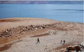  ?? Associated Press file photo ?? A family walks over cracked mud near the shore of California’s Lake Oroville last August, when it was at 68 percent of its historical average supply.