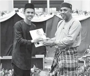  ??  ?? MOHD Zain menyerahka­n cenderamat­a kepada salah seorang pelajar yang menyertai Majlis Khatam Al-Quran.