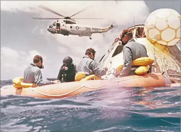  ??  ?? Apollo 12 astronauts wait to be airlifted after splashing down in the Pacific on November 24, 1969