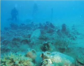  ?? GEO DELVEROUDI­S/THE ASSOCIATED PRESS ?? Derek Smith takes measuremen­ts at the site of an ancient shipwreck.