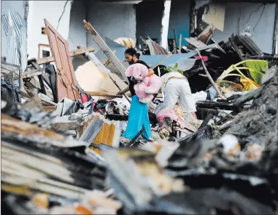  ?? Aaron Favila ?? The Associated Press A villager carries a stuffed doll he retrieved from a house Sunday in Palu, Indonesia. The death toll from the quake and a tsunami climbed to 1,763.