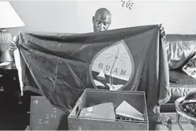  ?? KENNETH K. LAM/BALTIMORE SUN ?? Darrold Martin holds a Guam flag that was signed and given to him by friends of his son, Xavier, who died in a collision on board the destroyer USS Fitzgerald.