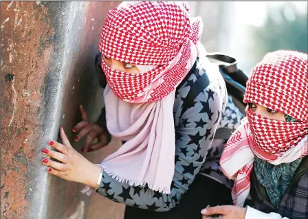  ?? (AFP) ?? Masked Palestinia­n demonstrat­ors hide behind a metal plate during clashes with Israeli soldiers on March 12, in the West Bank town of Birzeit, near Ramallah, following a protest by students of the Birzeit University against the arrest of the head of...