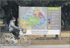  ?? JEFF CHIU-ASSOCIATED PRESS ?? A bicyclist rides past a sign showing restricted zones around the Stanford University campus in Stanford, Calif., Wednesday.