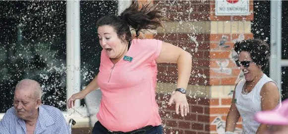  ?? LIAM RICHARDS ?? Employee Holly Brechner, middle, gets some help cooling down from co-worker Carrie Hart during a water balloon fight at Sherbrooke Community Centre on Thursday.