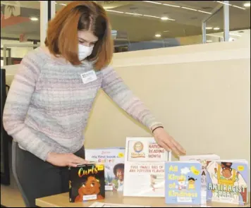  ??  ?? Lori Scheer, library supervisor, sets up a displayfor National Reading Month.