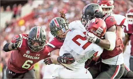  ?? File, Sean Rayford / The Associated Press ?? Arkansas’ Devwah Whaley (21) is tackled by South Carolina linebacker Skai Moore (from left), Dante Sawyer and T.J. Brunson during Saturday’s game.