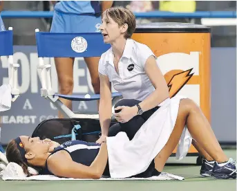  ?? PHOTOS: CATHERINE AVALONE/THE ASSOCIATED PRESS ?? WTA’s Martina Kehoe examines Monica Puig at the Connecticu­t Open. Puig withdrew from her match.