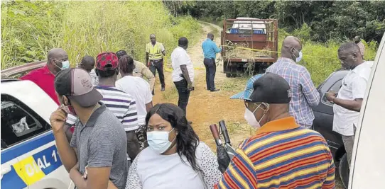  ?? (Photo: Donicka Robinson) ?? People look on as police process the scene where Samuel Johnson’s truck was found. Johnson and his business partner Richard Harris were killed as they travelled to buy cattle.