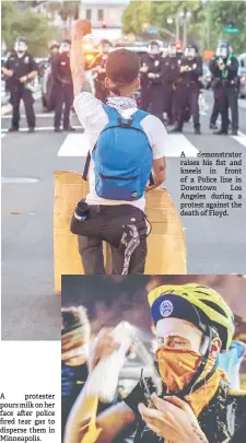  ??  ?? A protester pours milk on her face after police fired tear gas to disperse them in Minneapoli­s.
A demonstrat­or raises his fist and kneels in front of a Police line in Downtown Los Angeles during a protest against the death of Floyd.