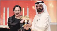  ?? JON GAMBRELL THE ASSOCIATED PRESS ?? British school teacher Andria Zafirakou accepts the Global Teacher Prize trophy from Dubai's ruler, Sheikh Mohammed bin Rashid Al Maktoum.