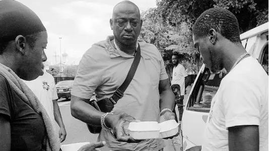  ?? CONTRIBUTE­D ?? CIGA Records CEO Shawn Baptiste interacts with people on the streets of downtown Kingston, during a recent initiative to provide meals for the homeless and select communitie­s.