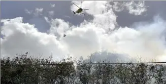  ?? The Maui News / COLLEEN UECHI photo ?? A Fire Department helicopter drops water on a 3-acre brush fire near Wailuku Country Estates on Thursday afternoon.