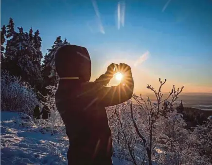  ?? AFP PIC ?? A tourist filming the sun setting on the winter landscape at the Grosser Feldberg mountain in Germany. Google has been introducin­g travel innovation­s in recent days and weeks.