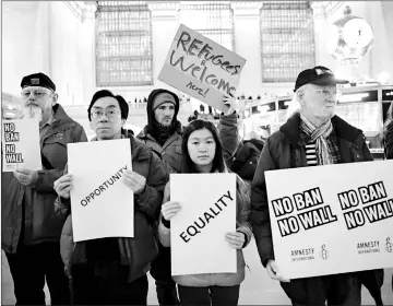  ?? — AFP photo ?? People stand holding placards as they take part in a protest called ‘No Ban! No Wall! Get Loud’ hosted by Amnesty Internatio­nal USA inside Grand Central Station in New York City.