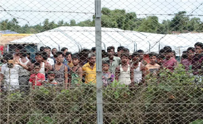  ?? AP ?? Rohingya refugees gather during a government- organized media tour in late June of a no- man’s land between Myanmar and Bangladesh in northern Rakhine State where thousands of Rohingya Muslims are still living.