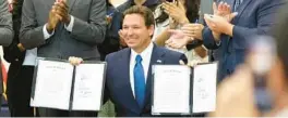  ?? RICH POPE/ORLANDO SENTINEL ?? Gov. Ron DeSantis holds up two house bills, HB 931 and HB 1317, after signing them during a news conference at Tohopekali­ga High School in Kissimmee on April 18.