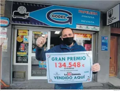  ?? PASCUAL ?? El administra­dor del despacho, Jorge Garzón, sostiene el importe del premio del boleto vendido en Papelería Godel.