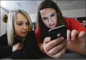  ?? GARY COSBY JR. / THE DECATUR DAILY ?? High school students Lissa Blagburn and Brantlee Wright use an iPhone as they work on a networked lesson in Spanish class in Hartselle, Ala. Cellphones are steadily gaining acceptance in U.S. schools, in part for security purposes.