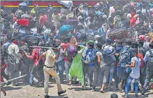  ?? AFP ?? A policeman disperses migrant workers outside a railway station in Mumbai on Tuesday. n