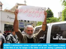  ?? — AFP ?? BEIRUT: A demonstrat­or carries a placard which reads “Don’t blame a sinner in the time of sin, for hunger is the father of all sin” during a gathering to denounce the death of a man who committed suicide in the capital’s Hamra Street on Friday.