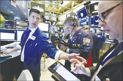  ?? AP PHOTO ?? Specialist Thomas Mcardle, left, works with traders John Panin, centre, and Jeffrey Vazquez on the floor of the New York Stock Exchange. U.S. stocks skidded Monday morning after China raised import duties on U.S. pork, apples and other products.