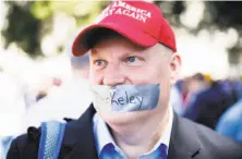  ??  ?? Daryl Lee Tempesta wears tape over his mouth while rallying with several hundred conservati­ve activists in the park.