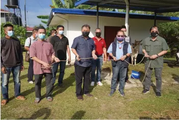  ??  ?? Kitingan (second right) handing over the cow to a representa­tive of Kampung Marampong, Keningau.