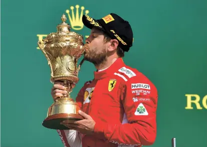  ??  ?? Ferrari’s German driver Sebastian Vettel kisses the trophy on the podium after winning the Formula One British Grand Prix at the Silverston­e circuit in Silverston­e, central England, yesterday. — AFP