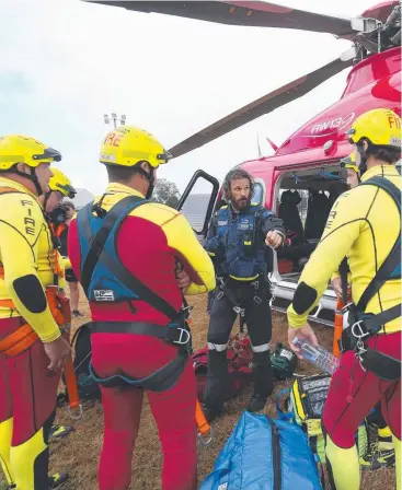  ?? Pictures: STEWART McLEAN ?? FINAL BRIEFING: Emergency services personnel prepare to fly out to rescue a kayaker who became trapped in the North Johnstone River near Malanda on Thursday afternoon.