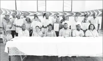  ??  ?? Some of the new leaseholde­rs (standing with their leases) along with Minister within the Ministry of Agricultur­e Valarie Patterson-Yearwood (seated third, from left), with GL&SC managers and regional officials after last Friday’s handing over. (GL&SC photo)