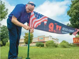  ?? AARON FLAUM/HARTFORD COURANT ?? Mcdonald’s Manager Ralph Pallozzi ties up a banner at the Glastonbur­y Mcdonald’s as signs are posted to remember 9/11 on Sept. 8. Portions of Monday’s sales were to go to the 9/11 Memorial Fund.