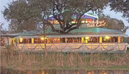  ?? WILL DICKEY/FLORIDA TIMES-UNION ?? The lights of Whitey's Fish Camp are reflected on the waters of Swimming Pen Creek in 2005.