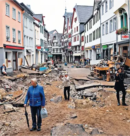  ??  ?? Soldiers try to recover a car from under a lorry in Erftstadt, above left; residents survey the debris left by the flood in Bad Münstereif­el, above