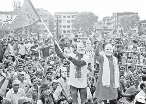  ?? — AFP photo ?? Indian political supporters of BJP wave a party flag as they wear masks of Modi during an election campaign led by Modi in Kolkata.